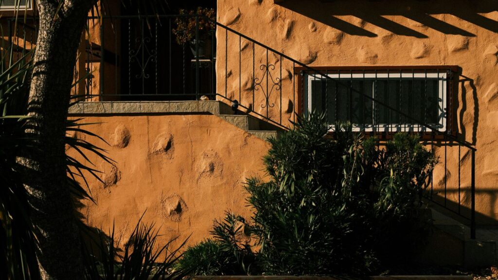 Exterior of a stucco house with stairs and plants.