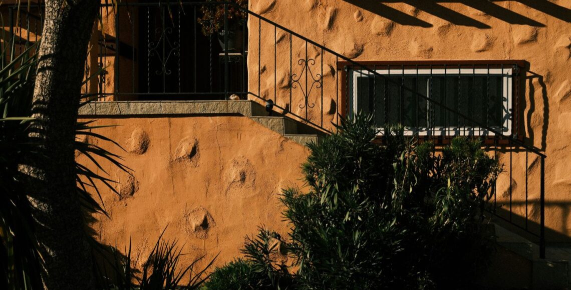 Exterior of a stucco house with stairs and plants.