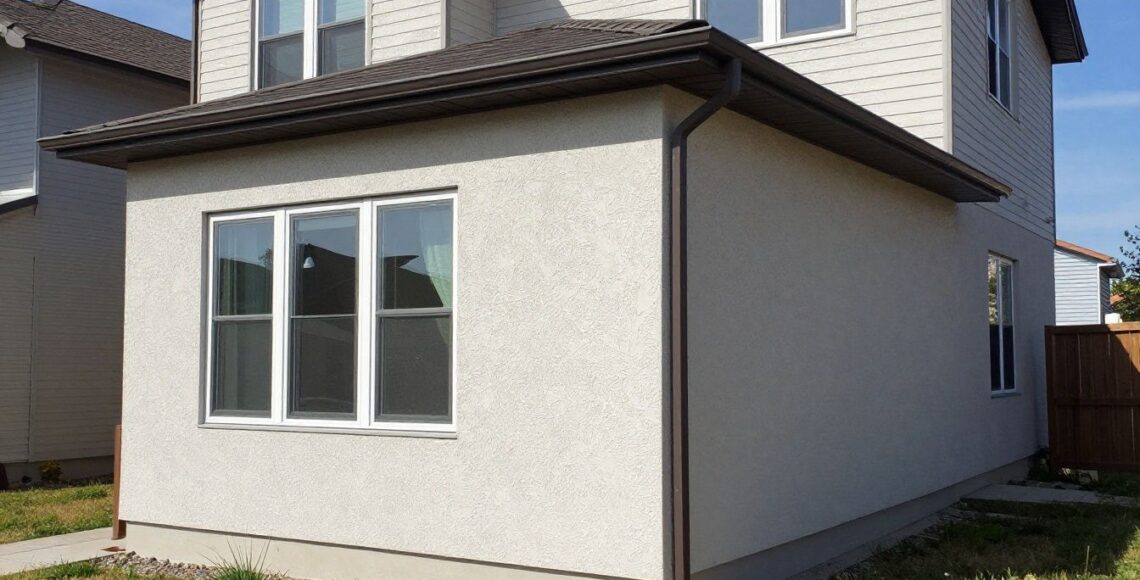 A modern residential home in the Chicago area featuring clean, well-maintained stucco siding, captured during a bright, clear day, showcasing the texture and quality of the exterior finish.